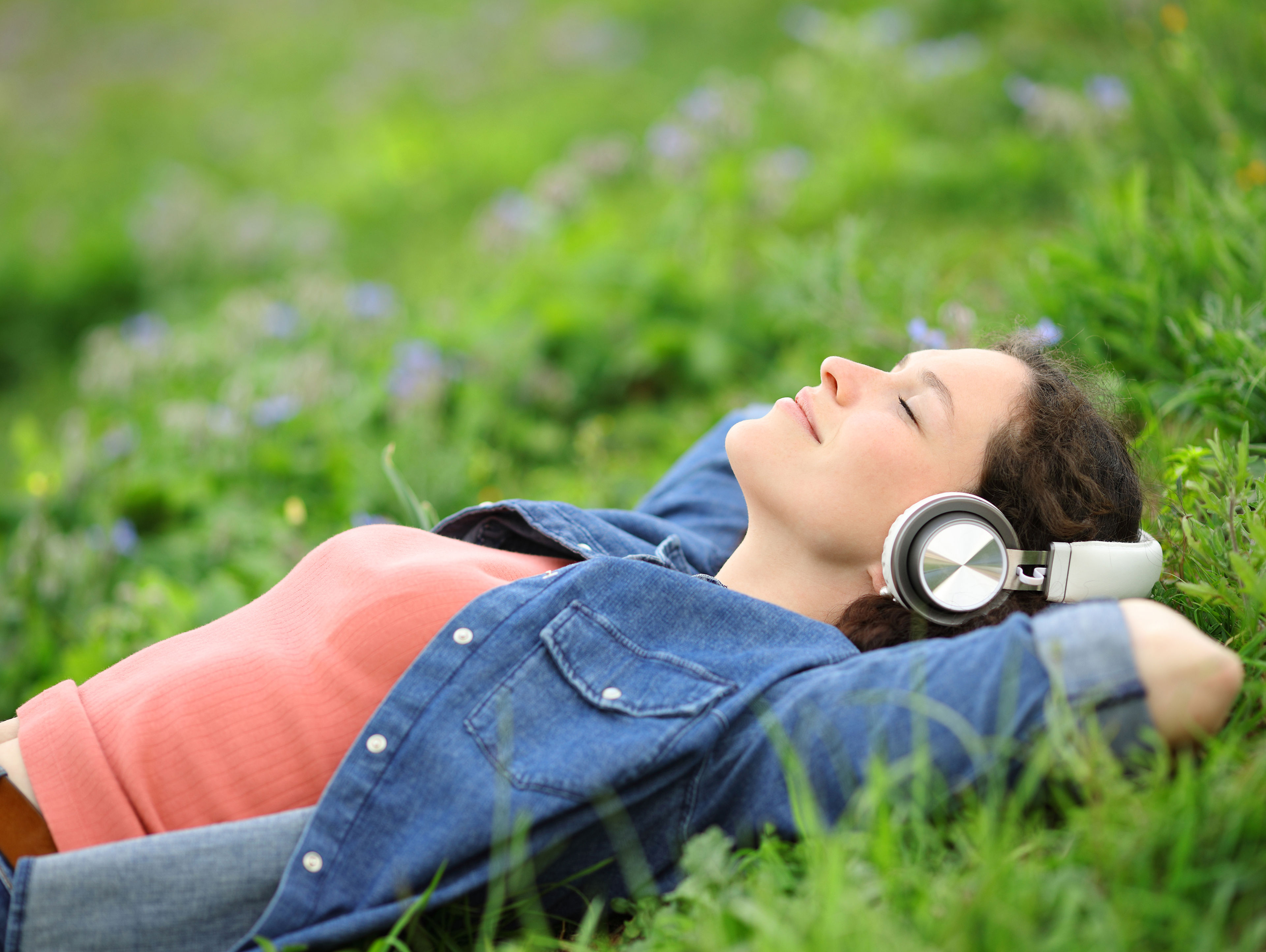 Relaxed Woman Lying On The Grass Listening To Music