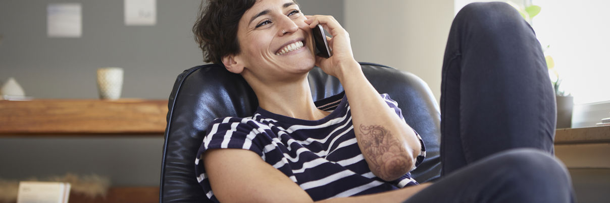 Happy Woman Talking On Cell Phone At Home