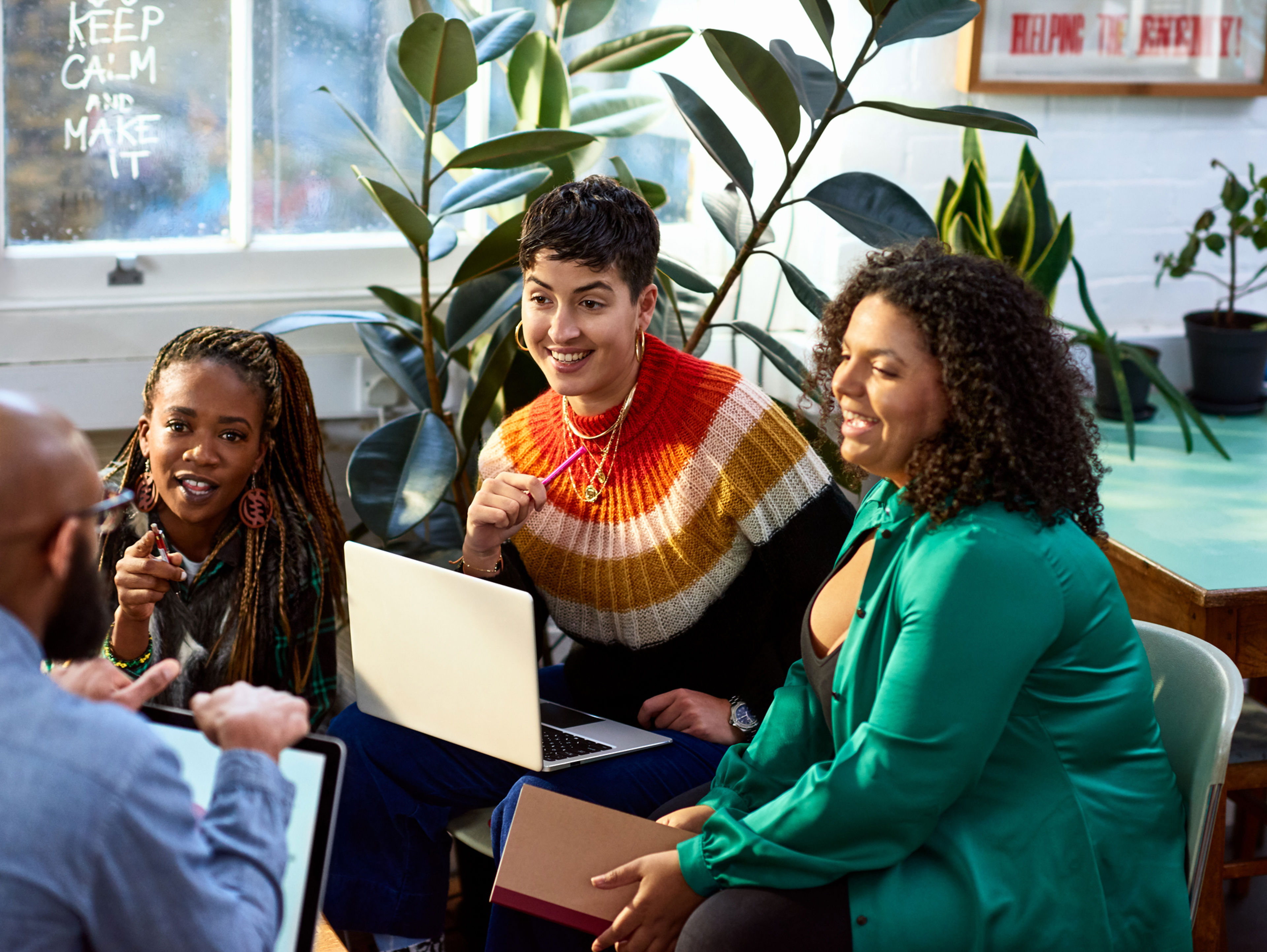 Group of co-workers huddled around laptops having a friendly conversation