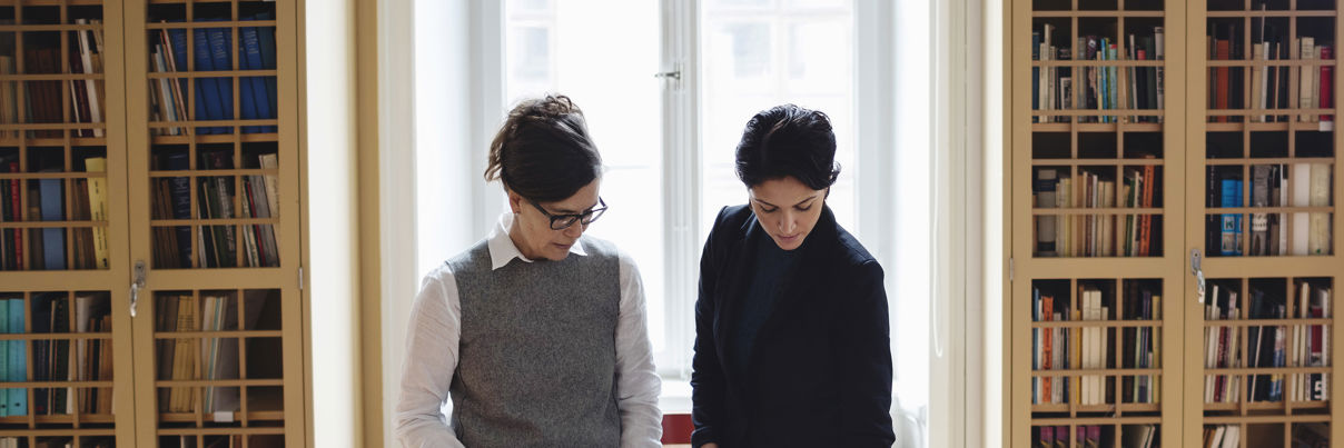 Female Lawyers Using Technologies At Table In Library