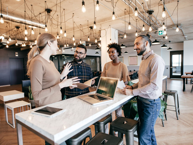 Group of co-workers standing around bench discussing work