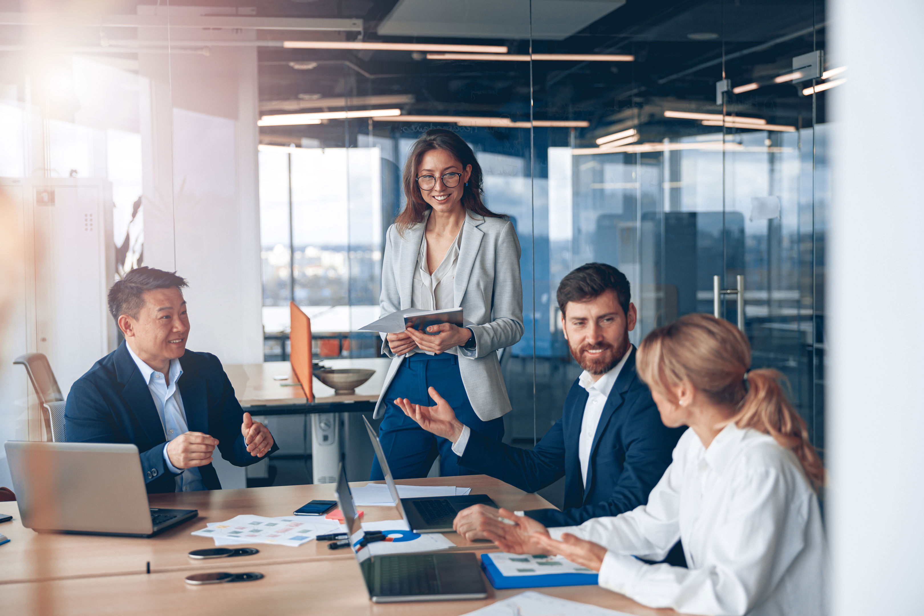 Group of co-workers in an office huddled around table having a discussion