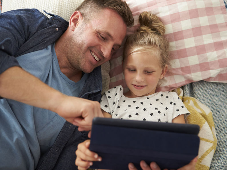 Father And Daughter Looking At Tablet