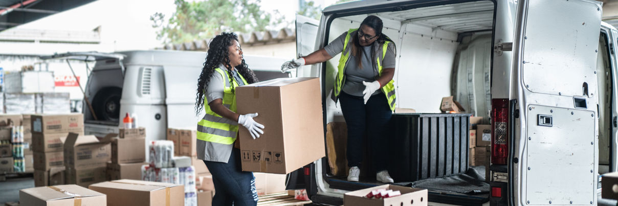 Warehouse workers loading van with boxes