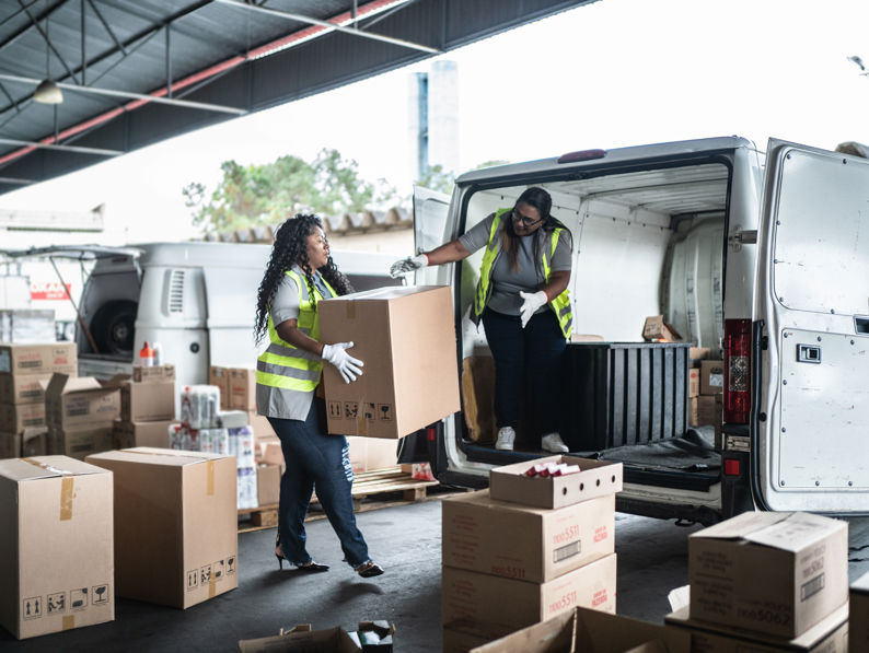 Warehouse workers loading van with boxes