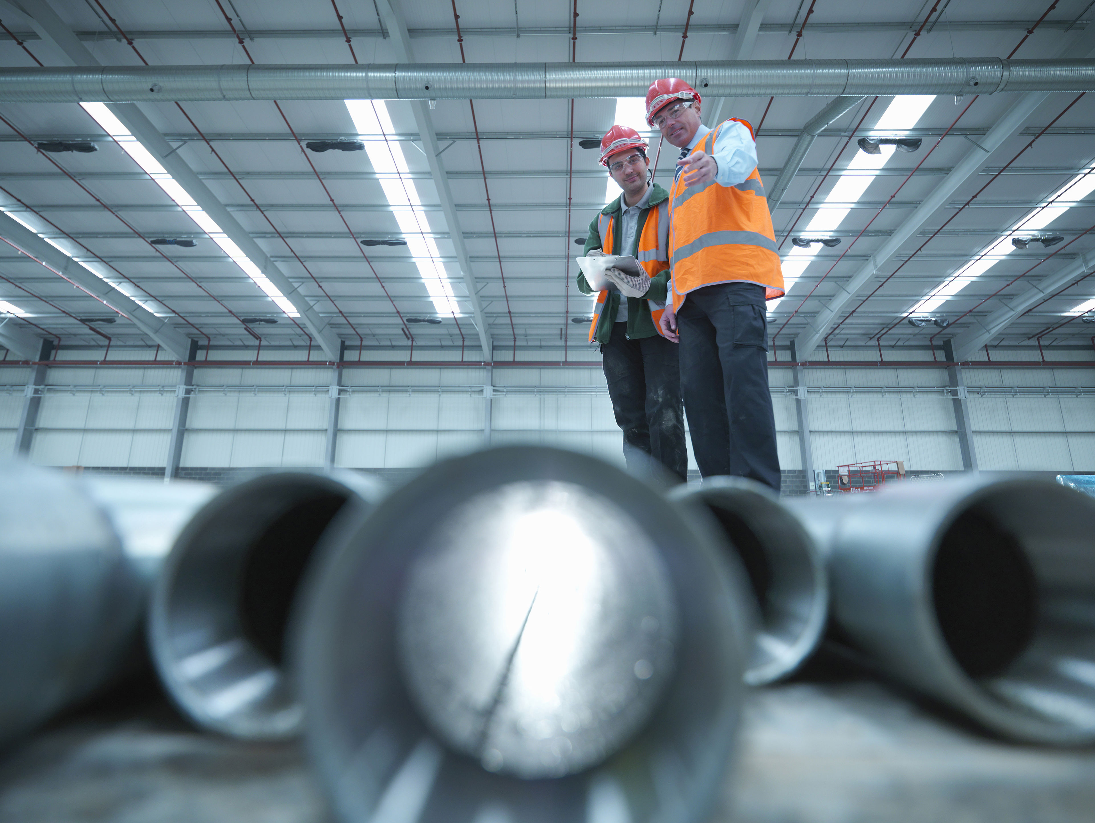 Workers Examining Pipes In Warehouse