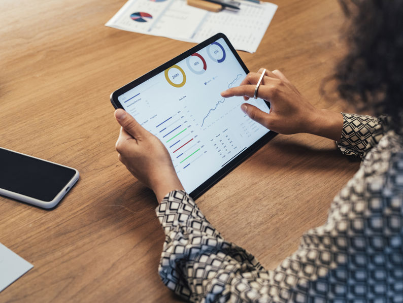 A businesswomen holding a tablet looking at graphs and tables