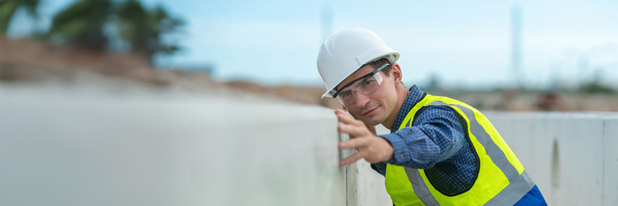 A young girl wearing a pink jacket and blue jeans sits on a curb, crying and covering her face while a group of kids nearby laugh and point at her.
