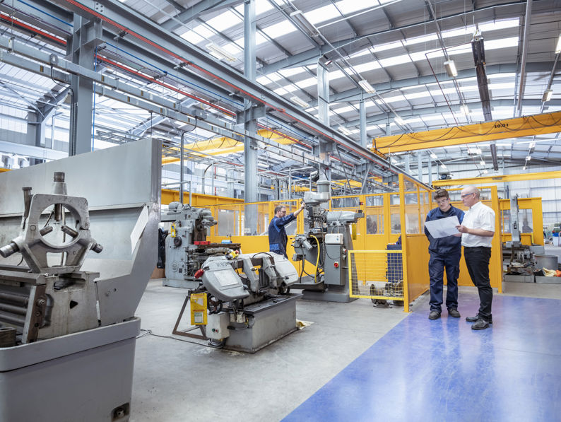 Three engineers working at a plant and discussing plans