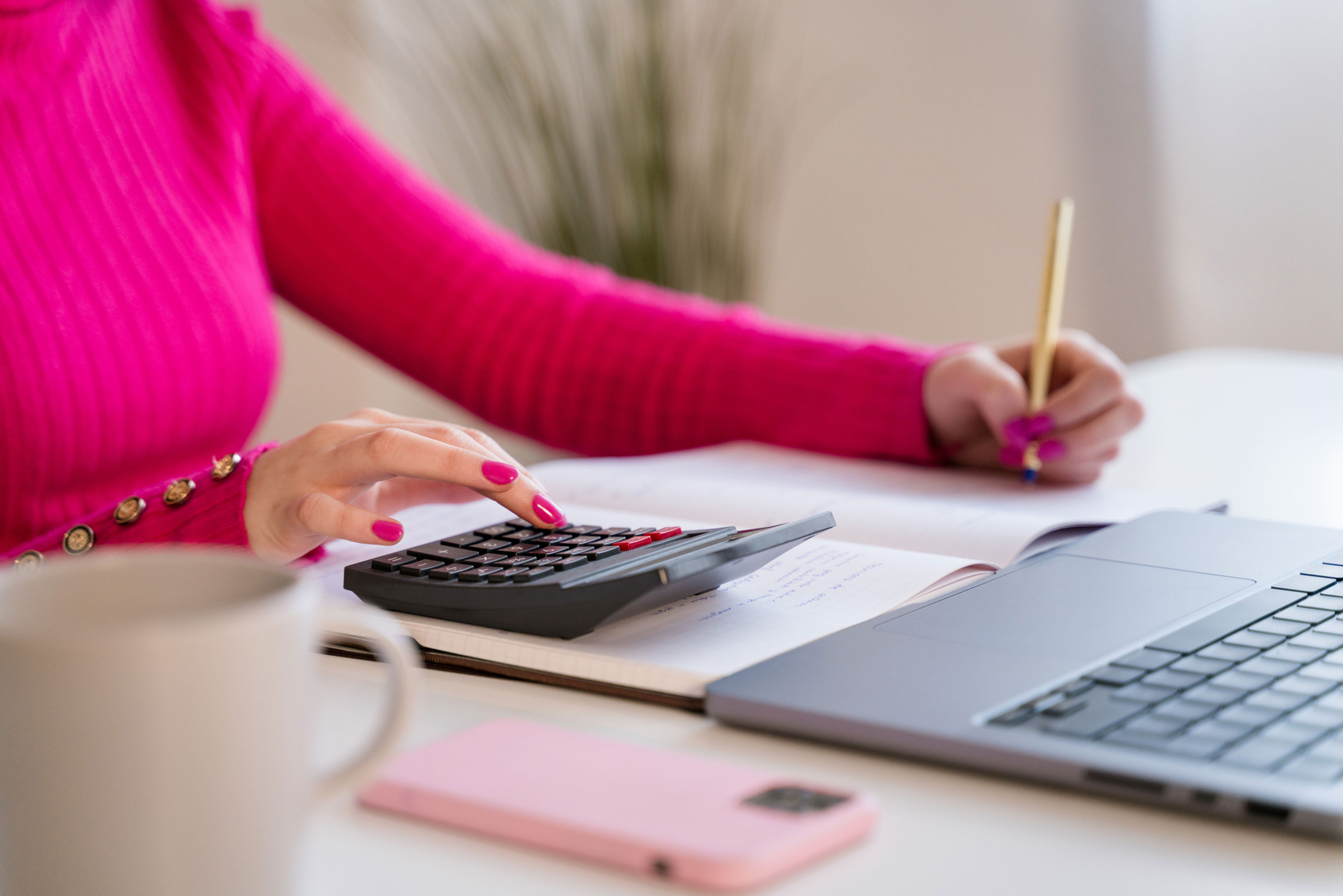 Women at a desk using a calculator and writing down information