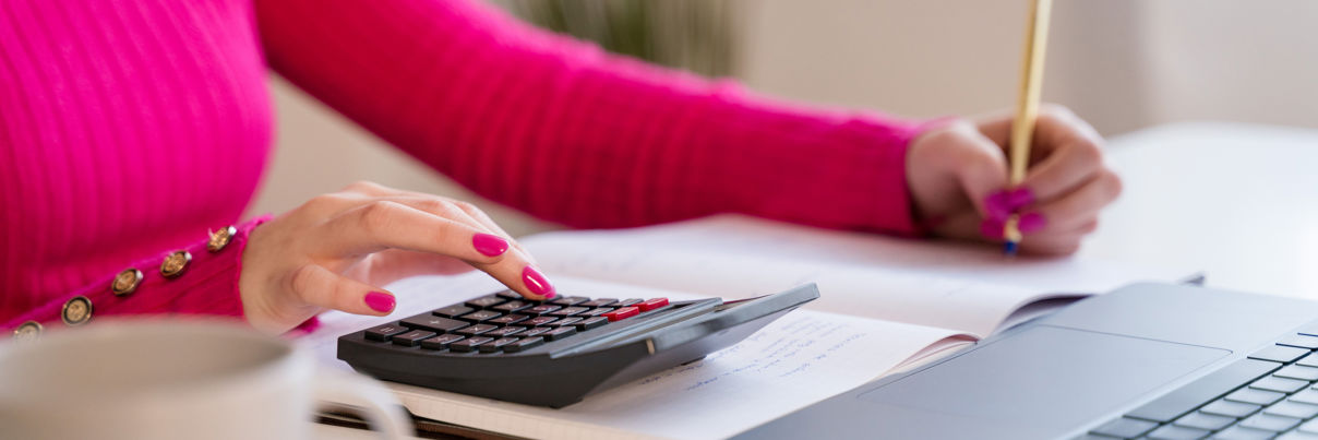 Women at a desk using a calculator and writing down information