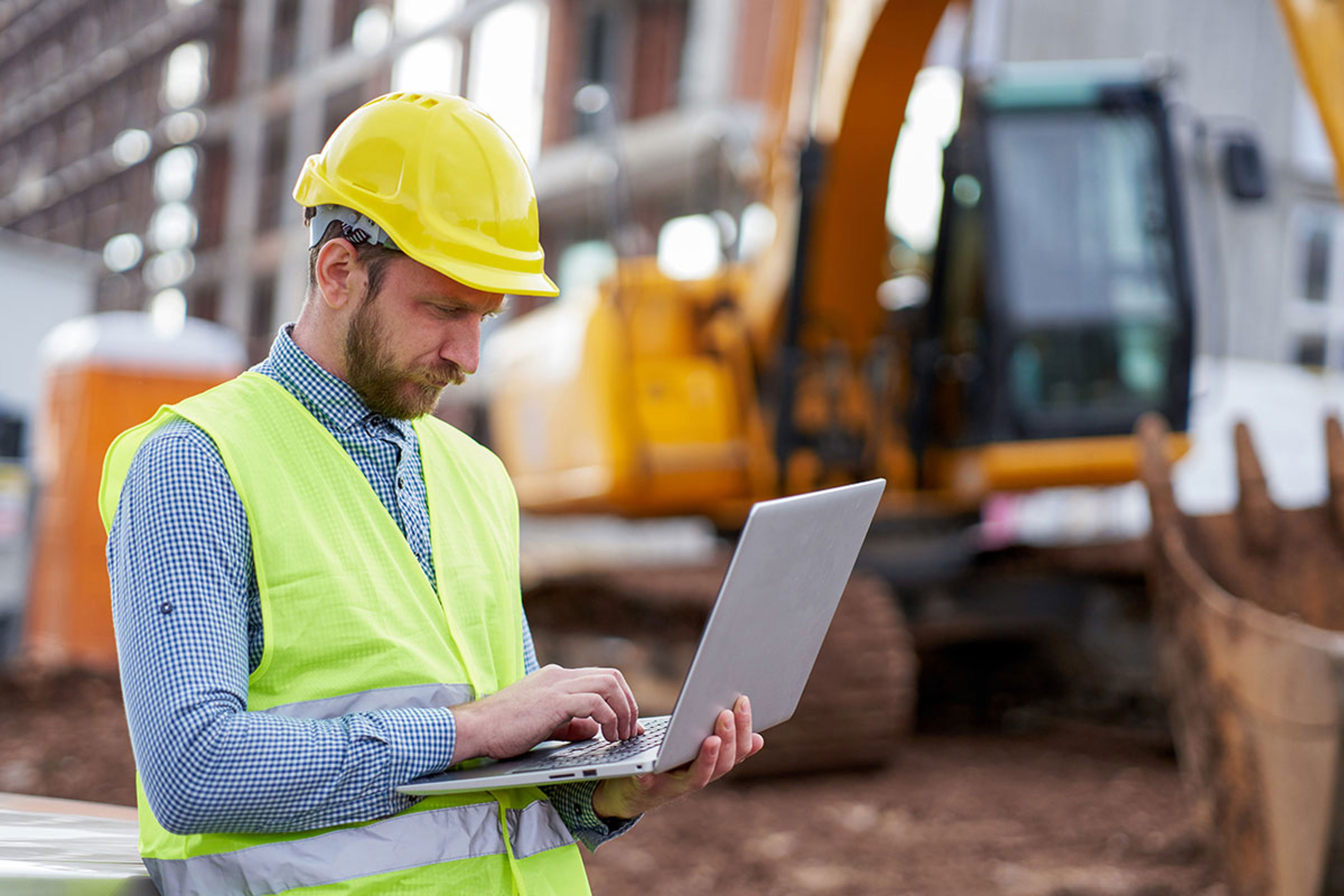 Man reviewing laptop on construction site