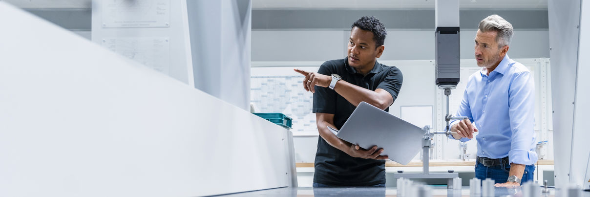 Engineer With Laptop Pointing By Businessman At Factory