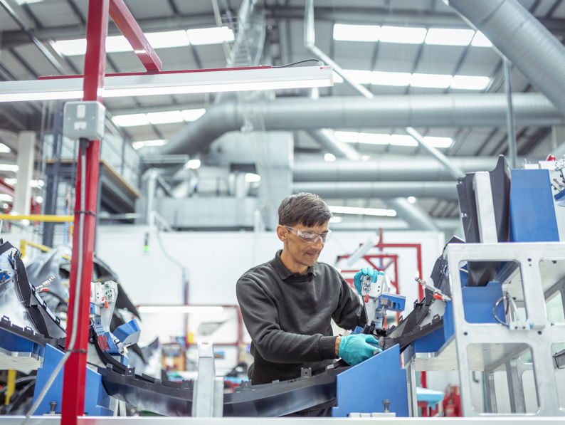 Worker assembling plastic injection moulded parts in automotive parts factory