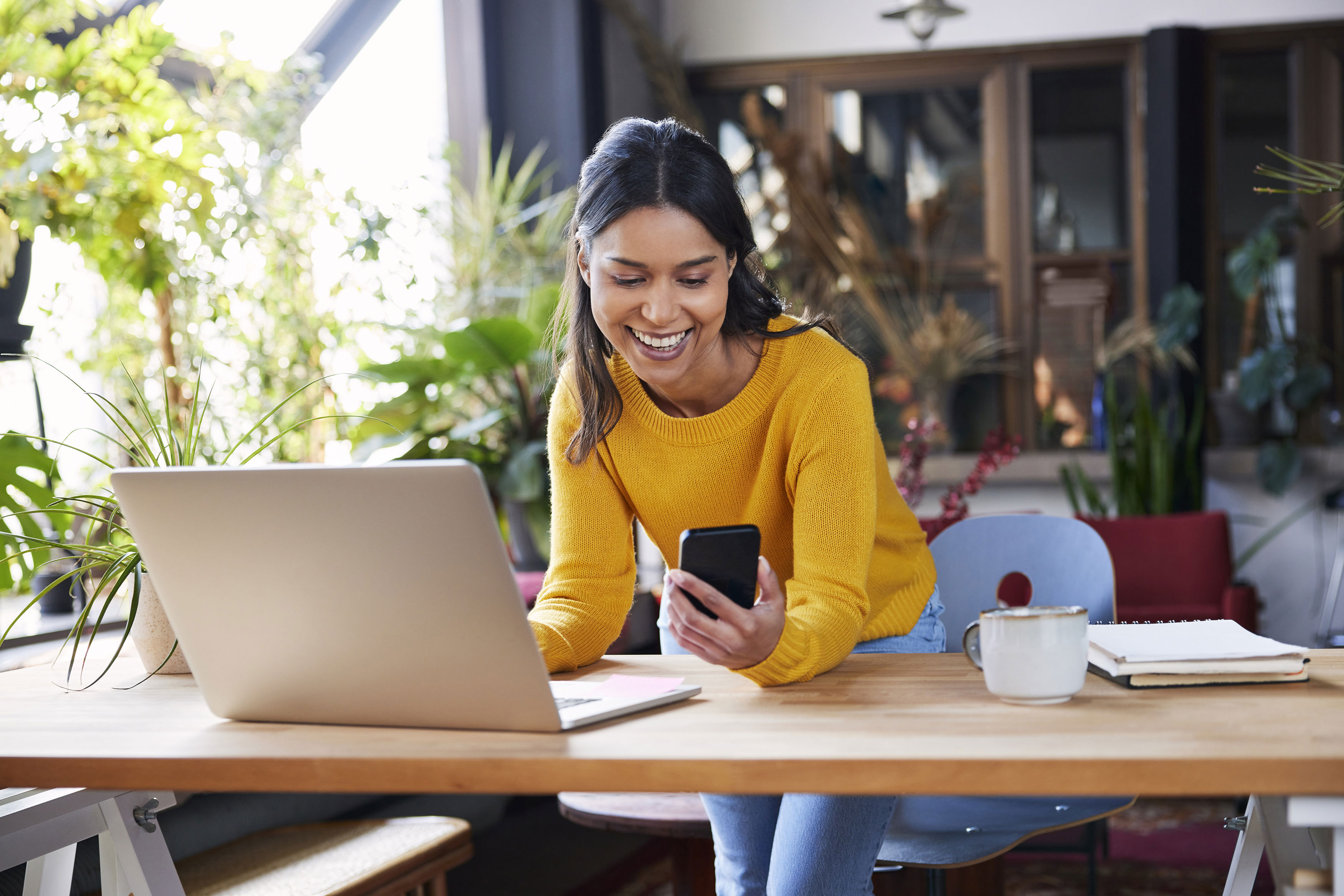 1 Smiling Businesswoman Using Mobile Phone Leaning On Desk At Loft Office (1)
